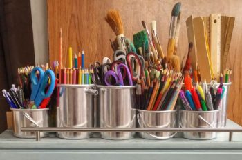 Silver buckets with pencils, markers, paint brushes, and other art supplies
