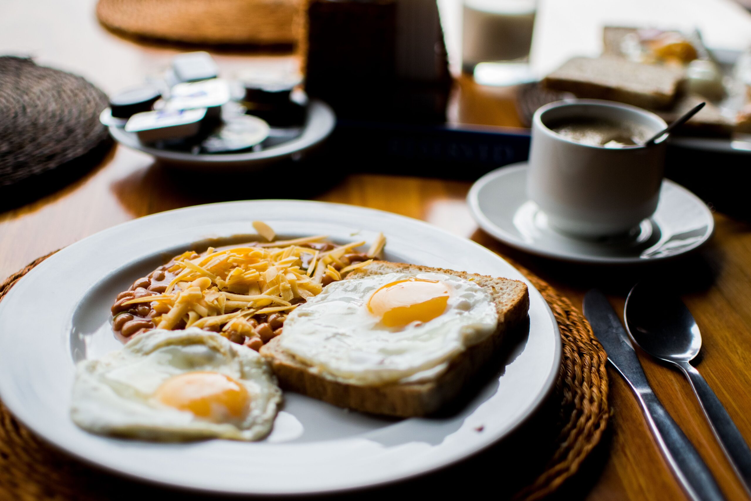 a plate with toast, eggs, and hash browns with a cup of coffee and other assorted breakfast items | breakfast